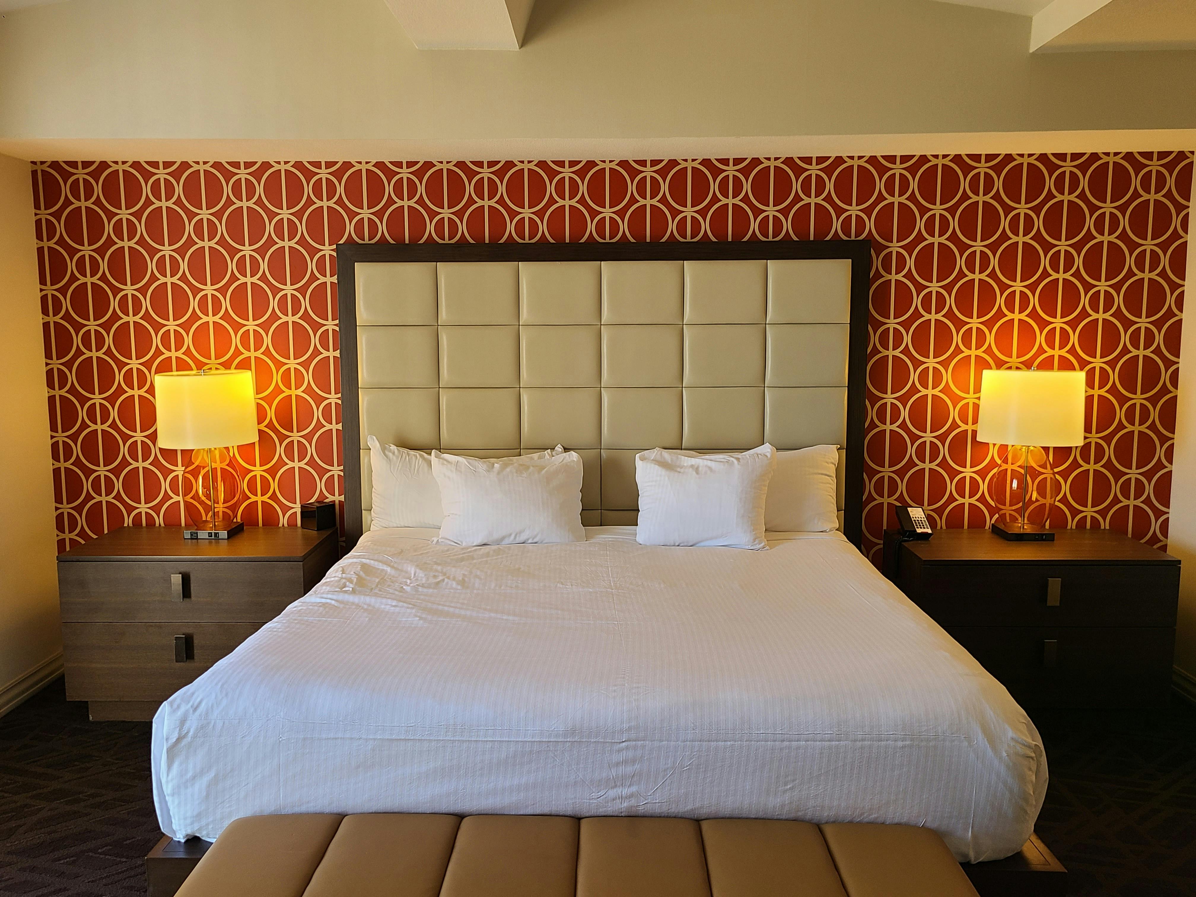 imagen de una cama con 2 pequeños muebles a sus costados