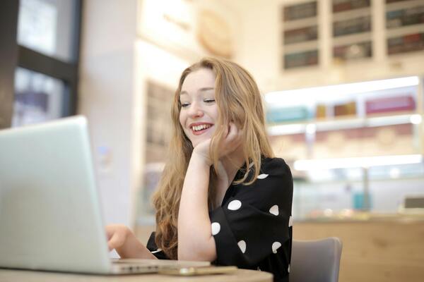 señorita sentada, mirando su laptop en la biblioteca